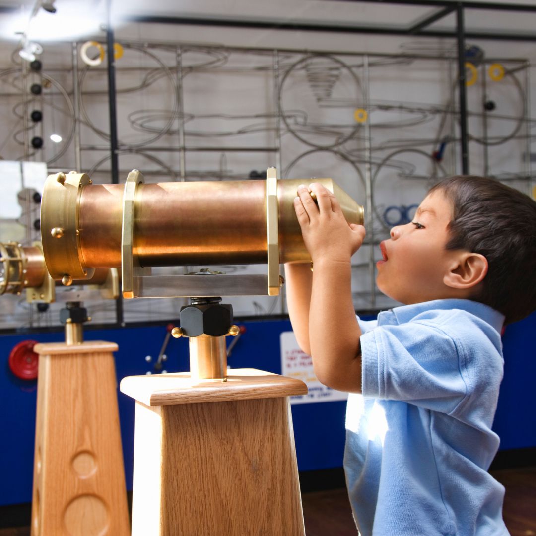Child at museum looking through telescope.