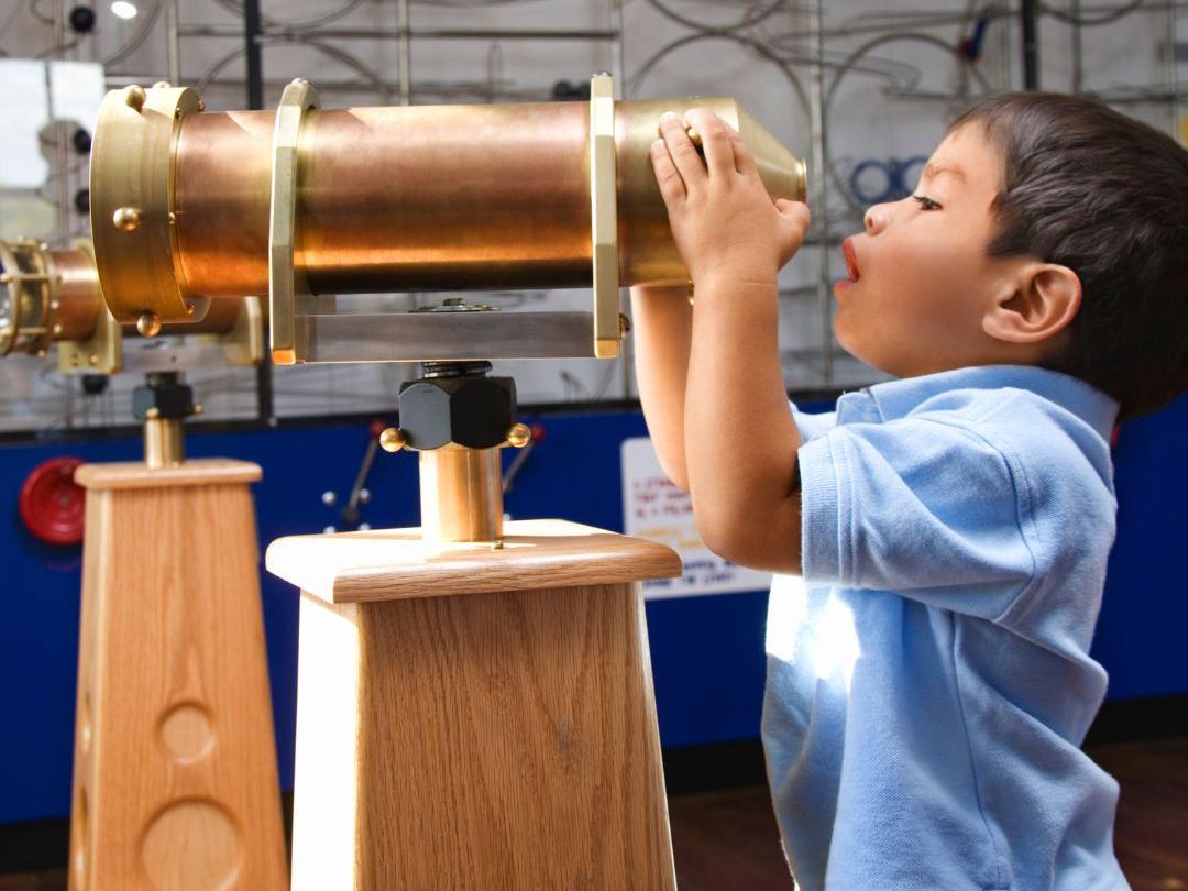 Child at museum looking through telescope.